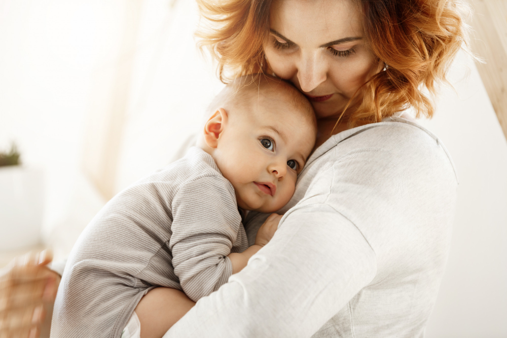 12204 beautiful young mother tenderly hugs her little cute child mom looking her kid smiling while baby looks aside snuggling mom chest happy family moments 8811597